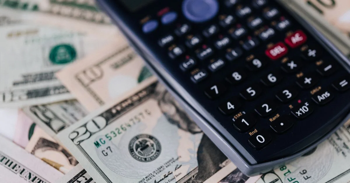 Prise de vue macro d'une calculatrice sur des billets de dollars américains, symbolisant la finance et le budget.